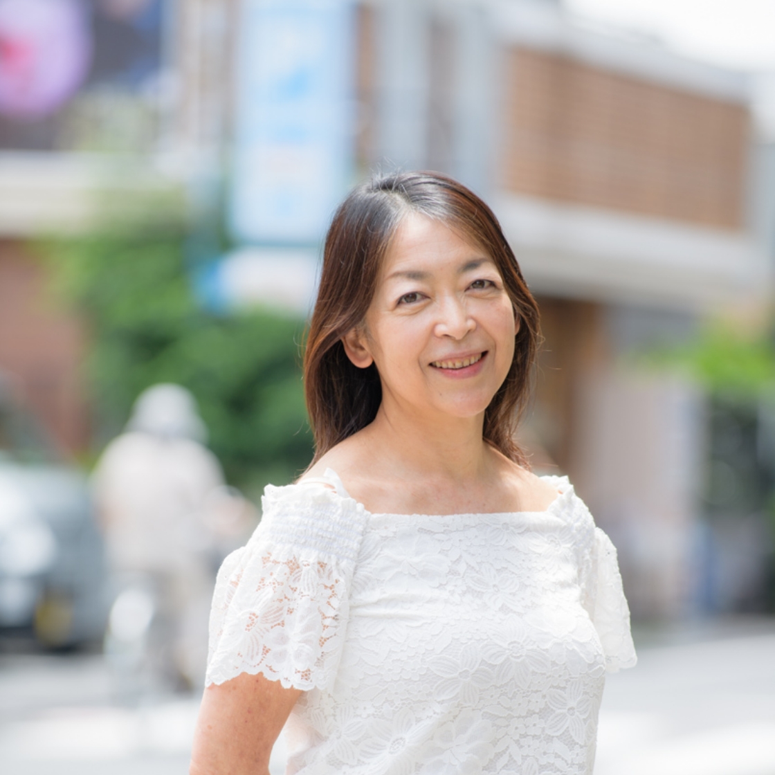 屋外で笑顔を見せる白いレースの服を着た女性
