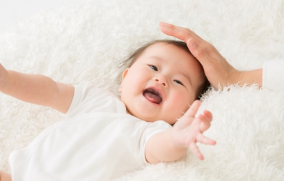 笑顔で手を伸ばす赤ちゃんと優しく触れる手