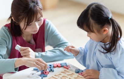 アルファベットパズルで遊ぶ子どもと講師