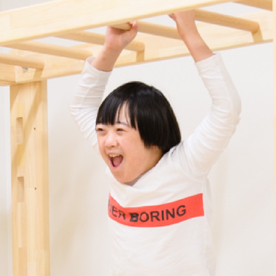 遊具にぶら下がって笑顔を見せる子ども