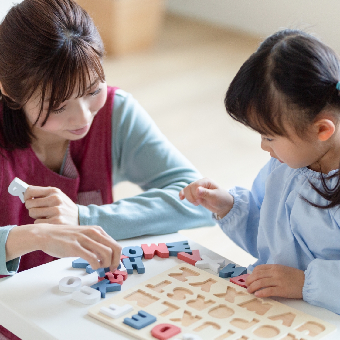 講師と子どもがアルファベットパズルで遊ぶ様子