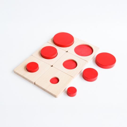 赤い円形ピースをはめるパズルのような教具